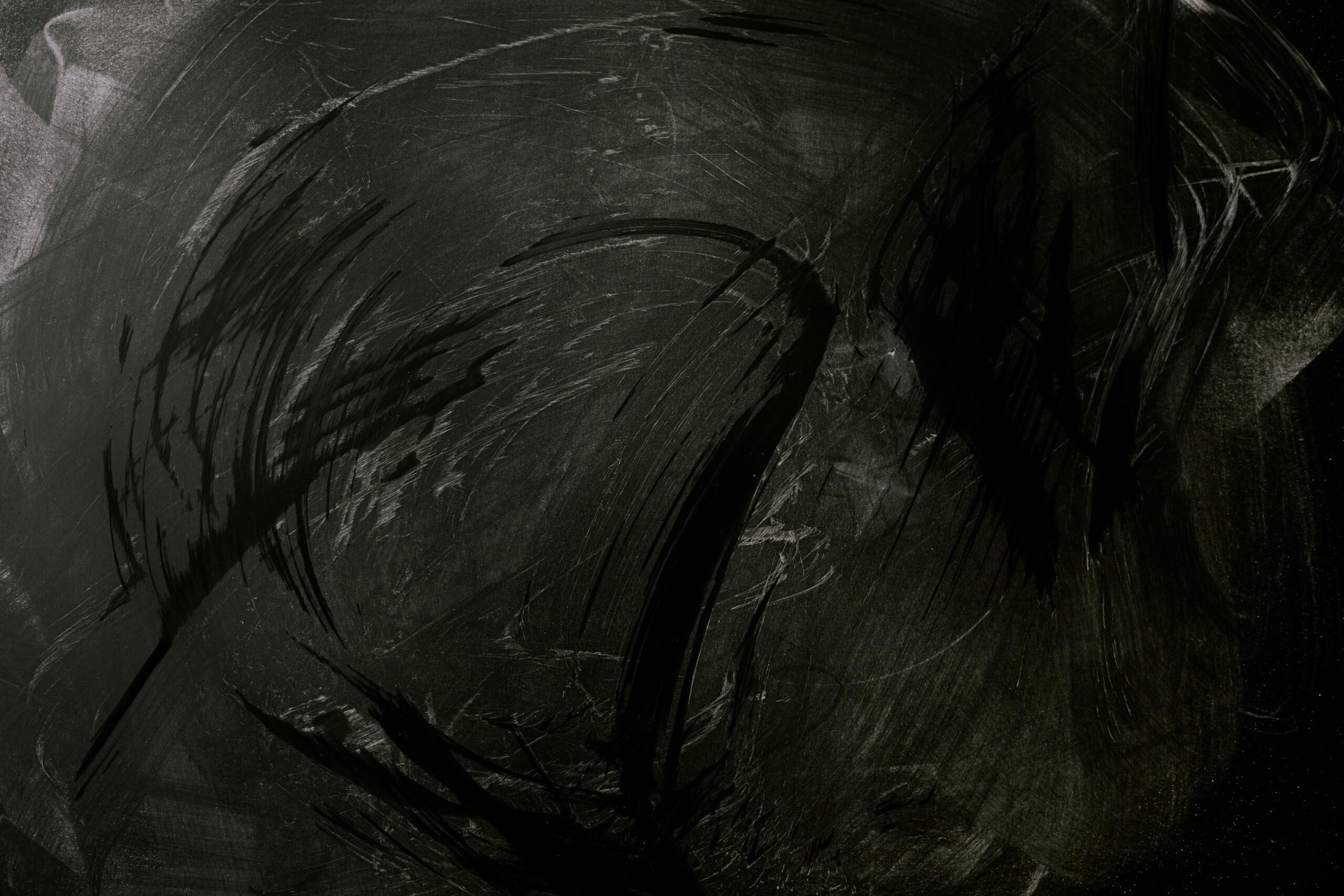 Intriguing black chalkboard with expressive chalk smudges, ideal for backgrounds or textures.
